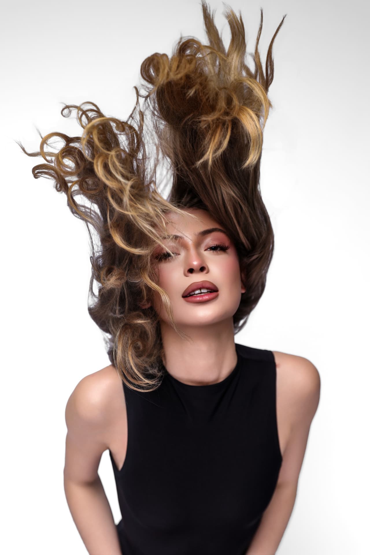 Model flipping dimensional blonde curls in an editorial toss